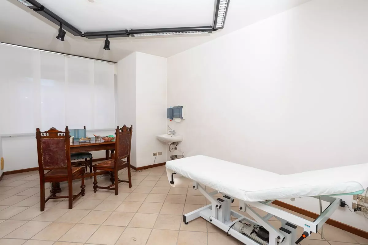 Contatti - Stanza del poliambulatorio Nuova Equipe con scrivania e un lettino in primo piano